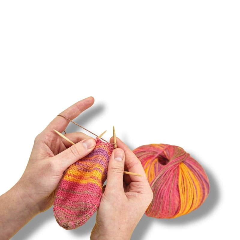 Handgestrickte Socke aus buntem Garn neben Addi 560-2 CraSyTrio BAMBOO Stricknadeln