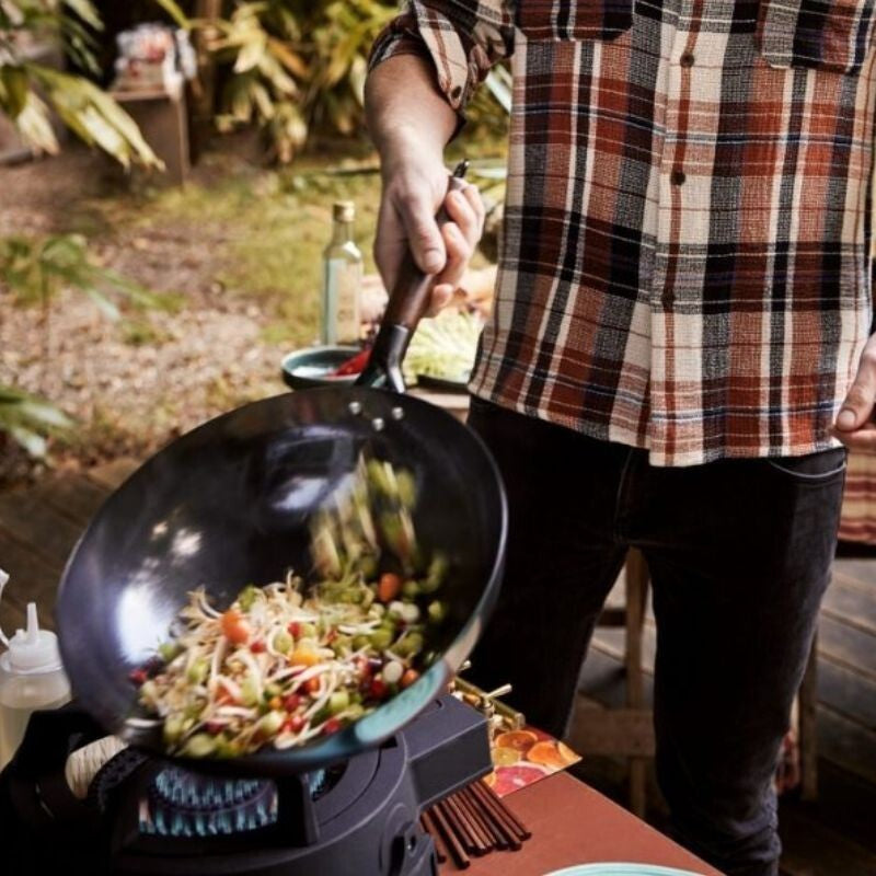 Person beim Gemüse und Nudeln im Grill Guru Easy Asia Wokbrenner kochen